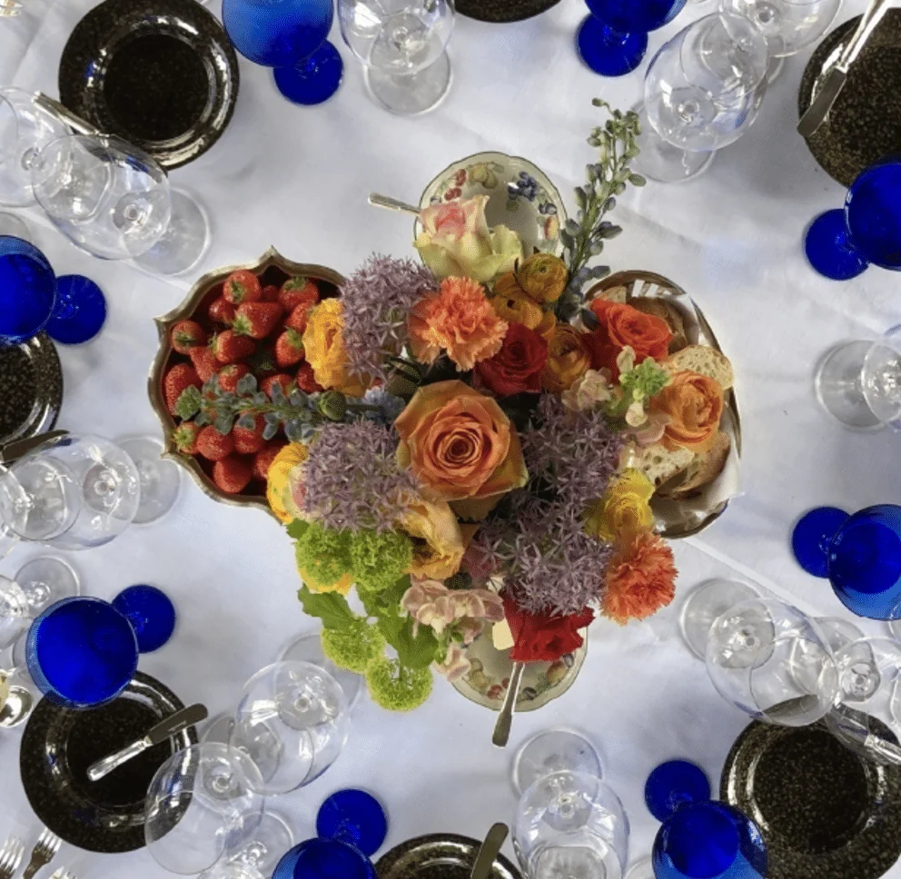 Feesttafel van bovenaf, met bloemstuk, aardbeien en blauwe glazen